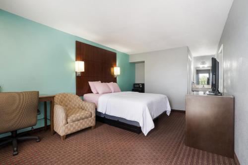 Un dormitorio con una cama, un escritorio y una silla. en Americas Best Value Inn and Suites Blytheville by Sonesta, en Blytheville