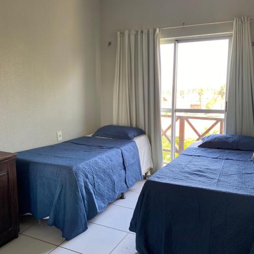 a bedroom with two beds and a window with a balcony at Flat Praia da Taíba - com vista Mar in Taíba