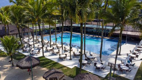 uma vista sobre uma piscina com cadeiras e palmeiras em Hotel Portobello Resort & Safari em Mangaratiba