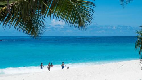 a group of people walking on a beach at Isle Royal Inn in Fuvahmulah