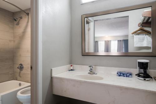Un baño con lavabo, espejo e inodoro. en Americas Best Value Inn and Suites Blytheville by Sonesta, en Blytheville