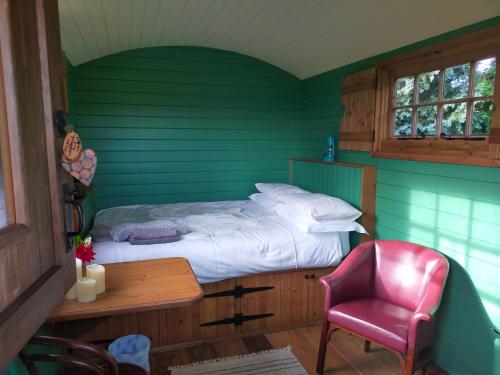 a green room with a bed and a desk and a chair at Lucker mill shepherds huts in Lucker