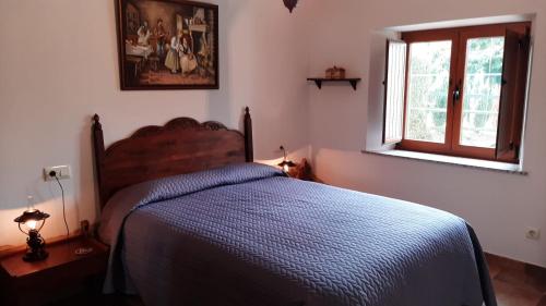 1 dormitorio con 1 cama con edredón azul y ventana en Stone Cottage FISTERRA en Curtis