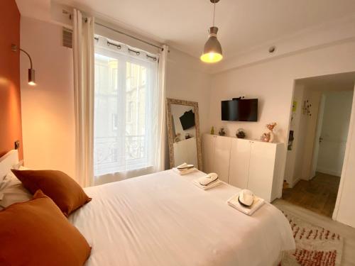 a bedroom with a large white bed and a window at Le Voltaire apartment - Paris Center in Paris