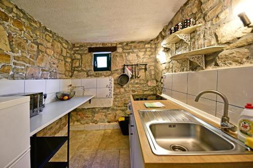 Villa Luna في موتوفون: مطبخ مع حوض وجدار حجري
