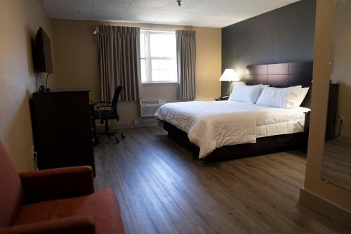 Habitación de hotel con cama y silla en Framingham Inn, en Framingham