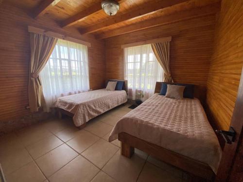 1 dormitorio con 2 camas y 2 ventanas en La Cabaña 2015, en Paso Ancho