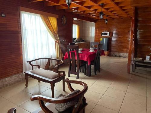 a dining room with a red table and chairs at La Cabaña 2015 in Paso Ancho