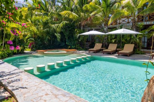 a pool with chairs and umbrellas in a resort at Muúnek Hotel Boutique Art & Spa in Barra Vieja