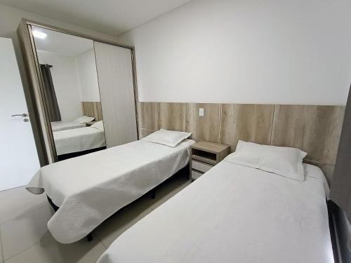 Habitación hospitalaria con 2 camas y espejo en Residencial Natália, en Bombinhas