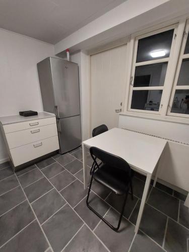 a kitchen with a white table and a refrigerator at Stuelejlighed med have og overdækket terrasse in Odense