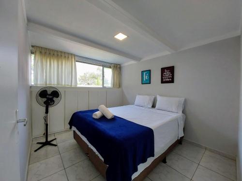 ein Schlafzimmer mit einem Bett mit einer blauen Decke und einem Ventilator in der Unterkunft Ao Lado do Aeroporto Com Vaga Coberta e Wifi 300 mb POWER in Guarulhos