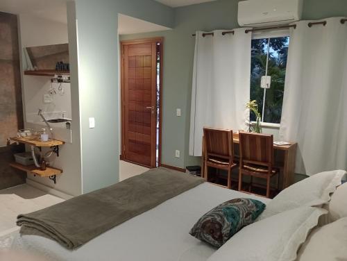 um quarto com uma cama, uma secretária e uma janela em Casa da Lu Itacoatiara -Suite Alto Mourão em Niterói