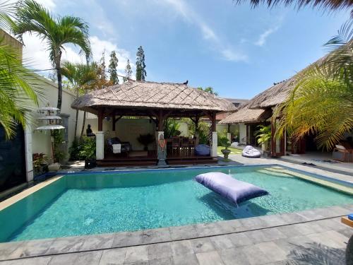 a swimming pool with a gazebo next to a house at Beautiful Villa Indah in Seminyak