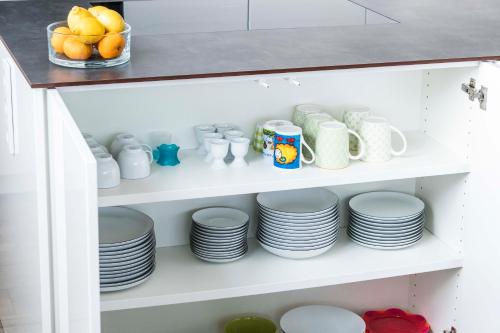 a shelf with plates and mugs and a bowl of fruit at Zweite Heimat in Lochau