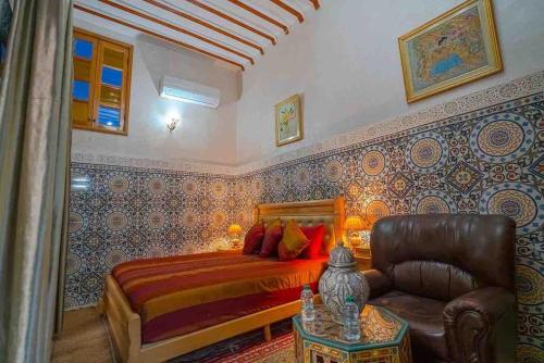 a bedroom with a bed and a chair and a table at Dar lmrama Guest House Fes Medina Morocco in Fès