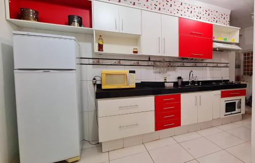 uma cozinha com armários vermelhos e brancos e um micro-ondas em Casa com banheira para até 12 pessoas prox USP-HC fácil acesso para Arena EUROBIKE com Wi-Fi em Ribeirão Preto