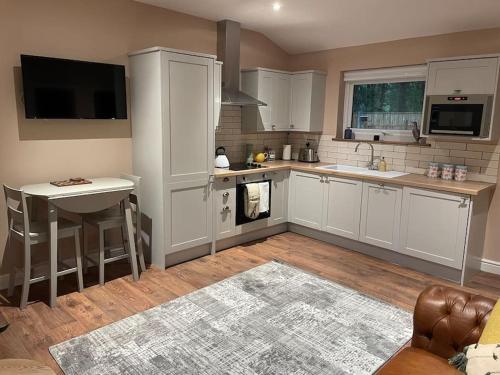a kitchen with white cabinets and a sink and a table at Tulip Cottage in Wisborough Green