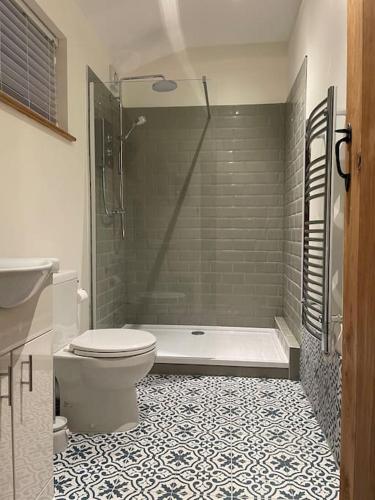 een badkamer met een bad, een toilet en een douche bij Tulip Cottage in Wisborough Green