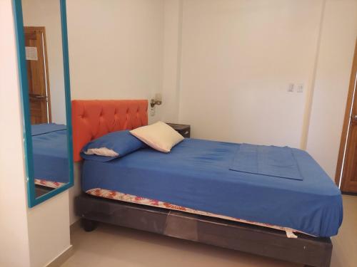 a bedroom with a blue bed with a orange headboard at Hotel Almond Beach in Tonsupa