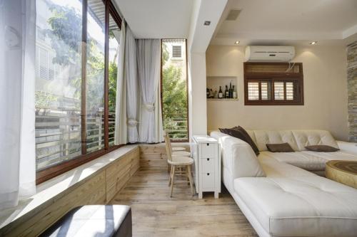 a living room with a white couch and a large window at Sunset TLV Apartment - Dizengoff 142 in Tel Aviv