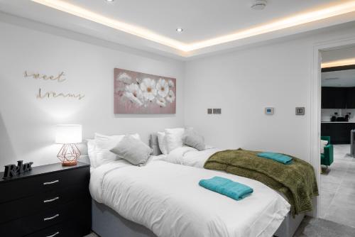 een witte slaapkamer met 2 bedden en een dressoir bij Aryas Apartments Newbury in Newbury