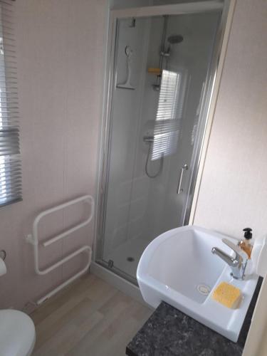 La salle de bains blanche est pourvue d'une douche et d'un lavabo. dans l'établissement le mobile home Le Victory situé au Camping Le Rio, à Noyelles-sur-Mer