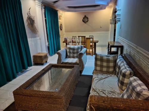 Mulia Homestay في باندا أسيه: غرفة معيشة بها كنب وكراسي وطاولة
