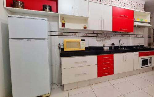 uma cozinha com um frigorífico branco e armários vermelhos em Casa com banheira para até 12 pessoas prox USP-HC fácil acesso para Arena EUROBIKE com Wi-Fi em Ribeirão Preto