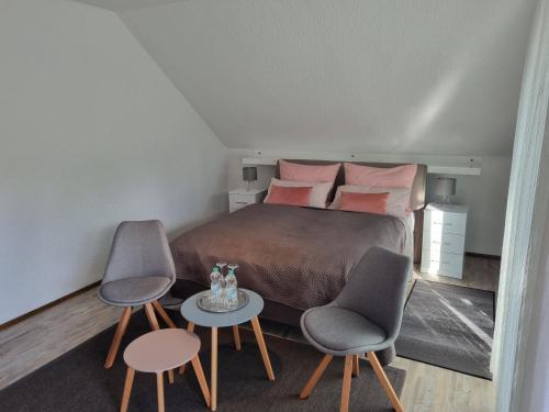 a bedroom with a bed with two chairs and a table at Haus Katarina in Wiesmoor