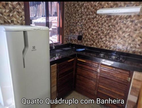 a kitchen with a refrigerator and wooden cabinets at Sanctuary Pirenópolis Suítes e Flats in Pirenópolis