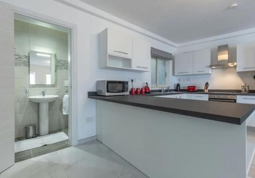 a white kitchen with a sink and a microwave at Sliema Bedrooms with ensuite bathrooms in Sliema