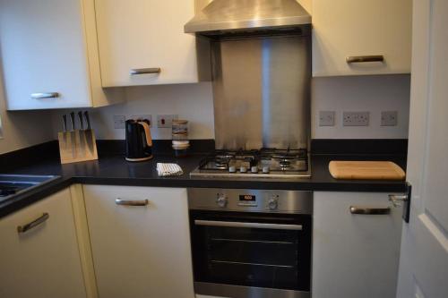 a kitchen with a stove and a counter top at Modern 2 Bed house - HS2, NEC & Birmingham Airport in Marston Green