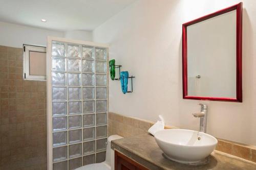 a bathroom with a sink and a toilet and a mirror at Golf Condo A1 F1: Nice view and access to the largest pool in Hacienda Iguana! in Rivas