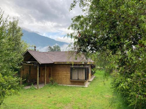 a small wooden house in the middle of a field at Cabaña En Lago colbun, sector Pasó Nevado in Talca