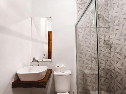 a white bathroom with a sink and a shower at Pousada Tamikuã in Caraíva