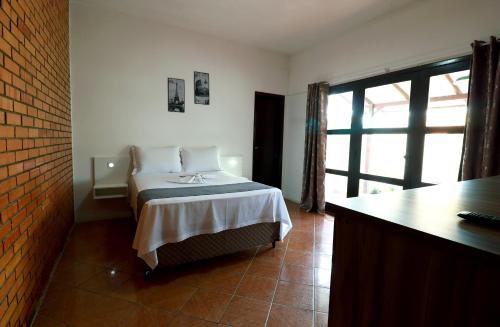 a bedroom with a bed and a large window at Pousada Navegantes in Navegantes