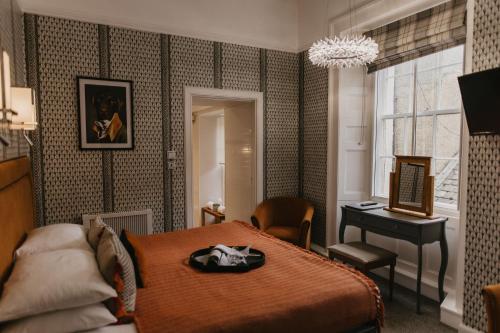a bedroom with a bed and a table and a piano at Atholl Arms Hotel Dunkeld in Dunkeld