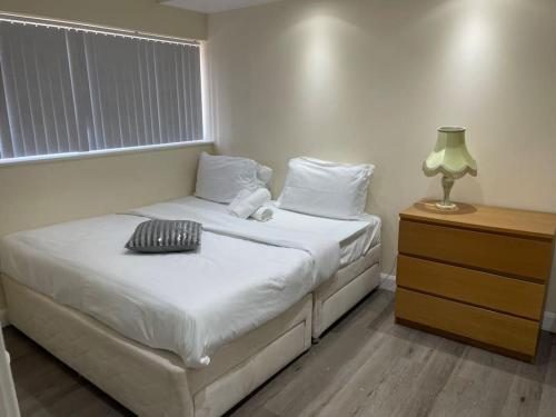 a bedroom with a bed with a lamp and a window at 5 Bedroom House by monishortlets in Dagenham