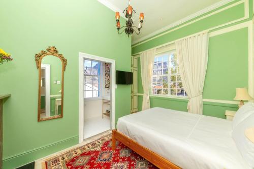 a bedroom with green walls and a bed and a mirror at Amina Boutique Hotel in Cape Town