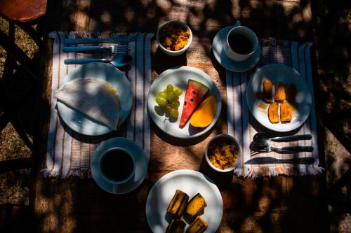 ein Tisch mit Tellern voller Essen auf einem Tisch in der Unterkunft Pousada Tamikuã in Caraíva