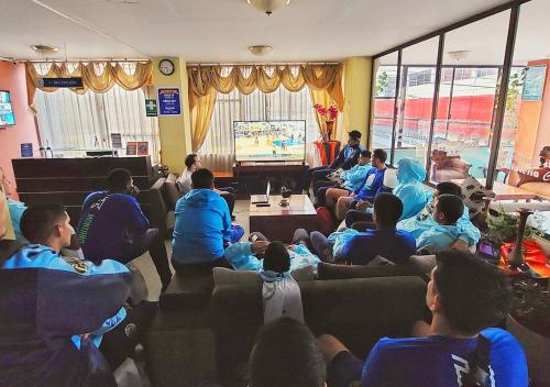 a group of people sitting in a room playing a video game at La Merced Plaza Hospedaje in Riobamba