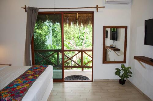 a bedroom with a bed and a large window at Aldea San Lam - Oasis Of Tulum in Tulum