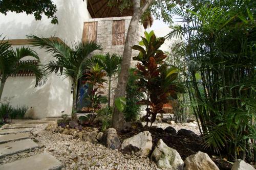 a garden with trees and rocks in front of a building at Aldea San Lam - Oasis Of Tulum in Tulum