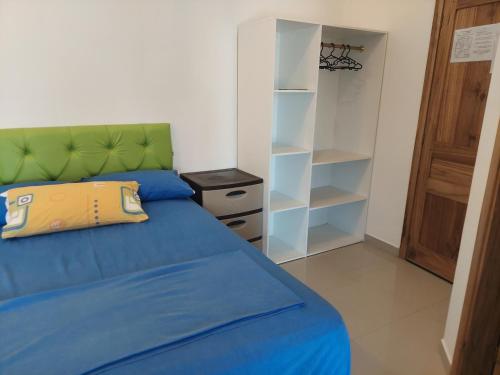 a bedroom with a bed with a green headboard and shelves at Hotel Almond Beach in Tonsupa