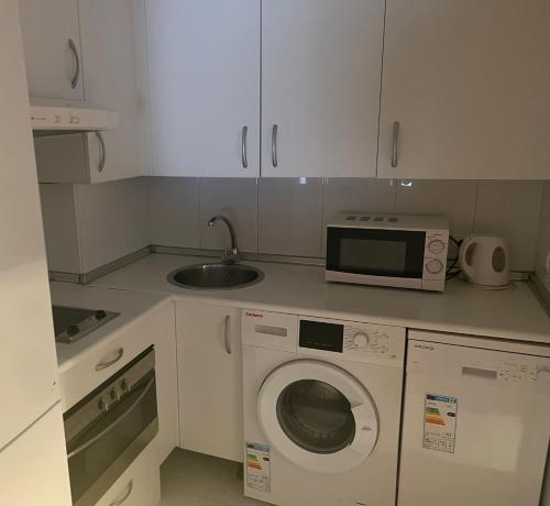 a kitchen with a washing machine and a microwave at Airport Madrid suites apartments Belfast 13 in Madrid