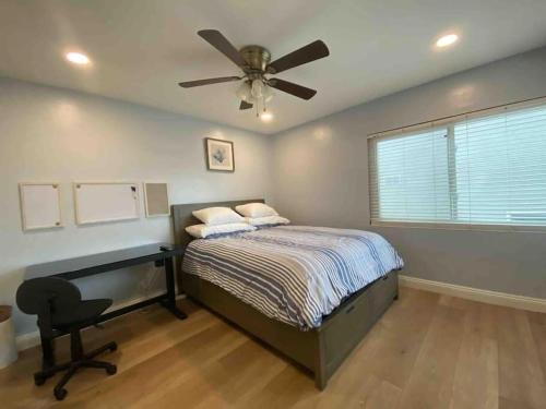 Blue Whale Inn San Clemente Charmer Unit A في سان كليمنت: غرفة نوم مع سرير مع مروحة سقف ومكتب