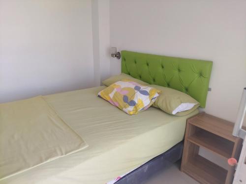a bed with a green headboard and two pillows on it at Hotel Almond Beach in Tonsupa