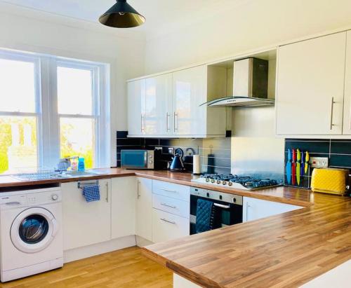 a kitchen with white cabinets and a washing machine at Lovely 2 bed specious flat with indoor fire place in Perth