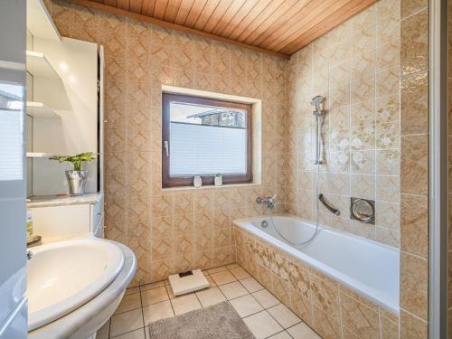 a bathroom with a tub and a toilet and a sink at Ferienhaus Rieder in Hopfgarten im Brixental